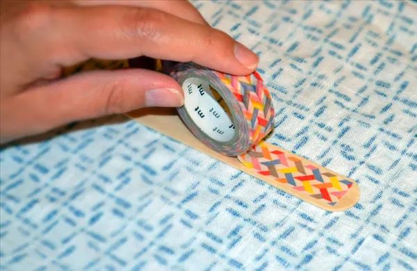 Putting washi tape on popsicle stick